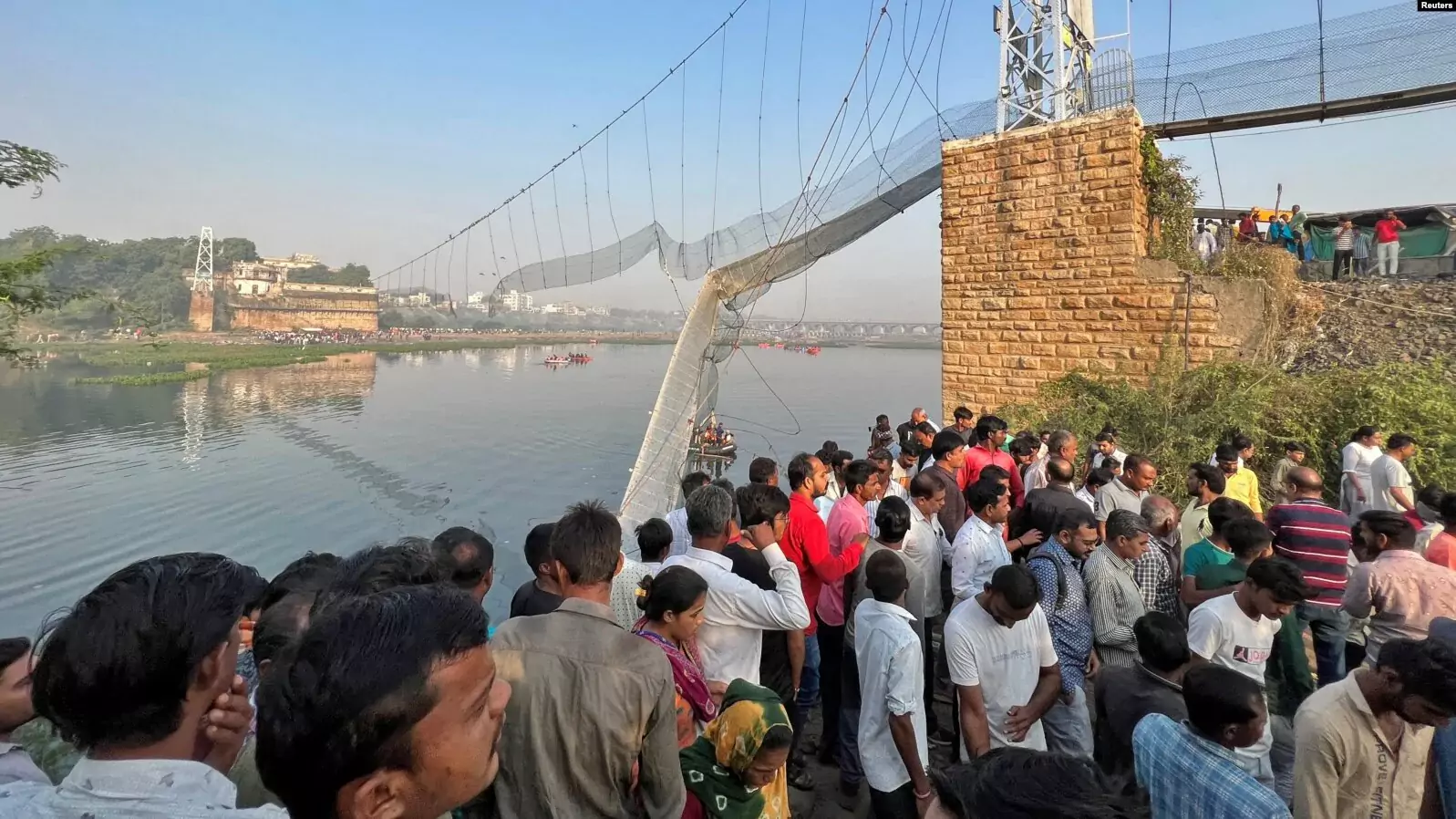 People gather as rescuers search for survivors after a suspension bridge collapsed in Morbi town in the western state of Gujarat, India, Oct. 31, 202
