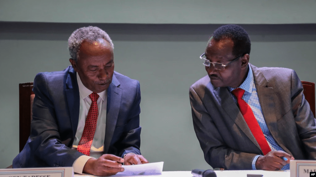Head of the Tigray Forces Lieutenant General Tadesse Werede, left, and Chief of Staff of Ethiopian Armed Forces Field Marshall Birhanu Jula read a copy of an agreement at Ethiopian peace talks in Nairobi, Nov. 12, 2022.